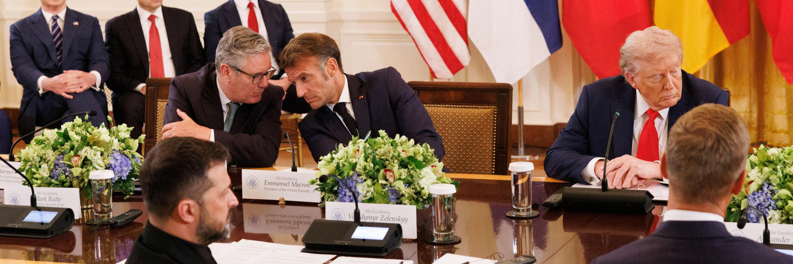 Keir Starmer and Emmanuel Macron talking while Donald Trump looks in the other direction.