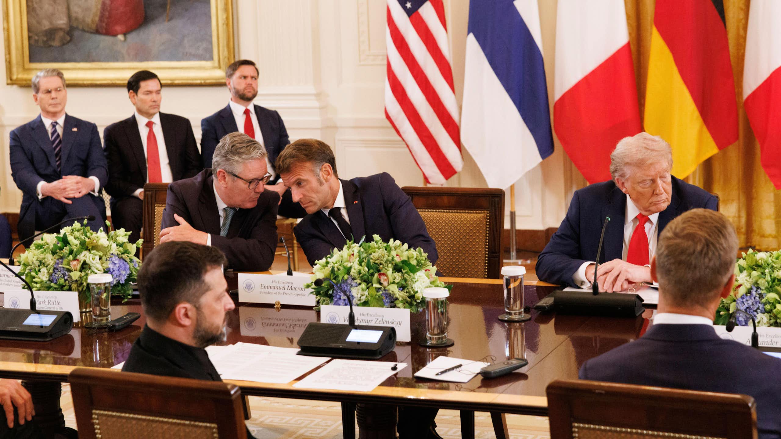 Keir Starmer and Emmanuel Macron talking while Donald Trump looks in the other direction.