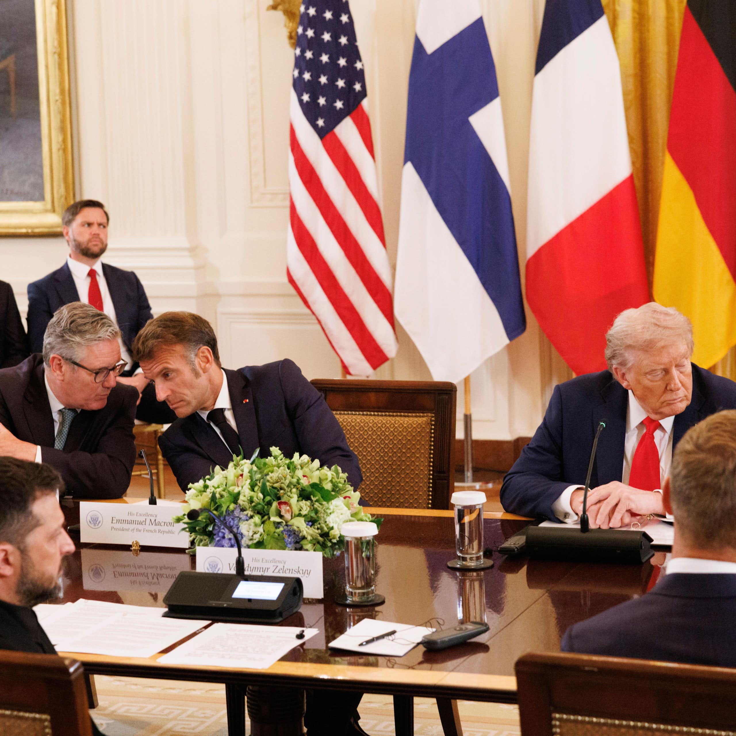 Keir Starmer and Emmanuel Macron talking while Donald Trump looks in the other direction.