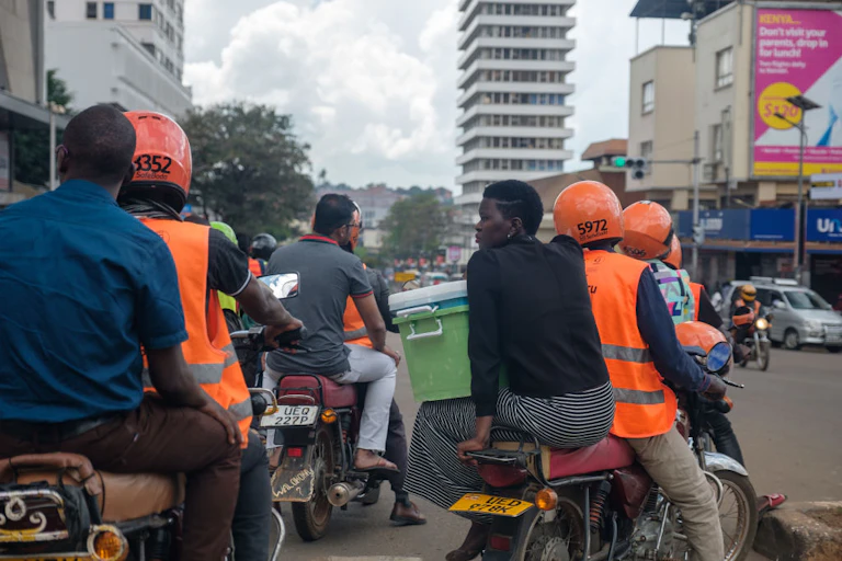 People in orange vests and helmets driving motorbikes with passengers on a city street