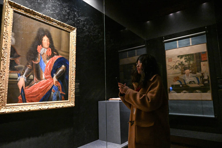 Une femme admirant le portrait de Louis XIV