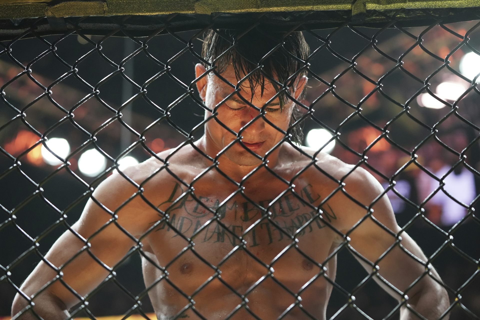 Un combattant UFC baisse la tête devant la grille de l'arène.