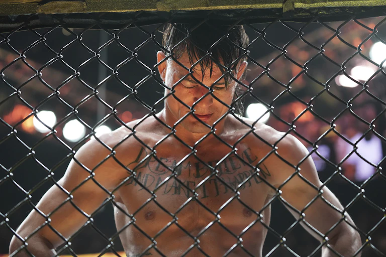 Un combattant UFC baisse la tête devant la grille de l'arène.