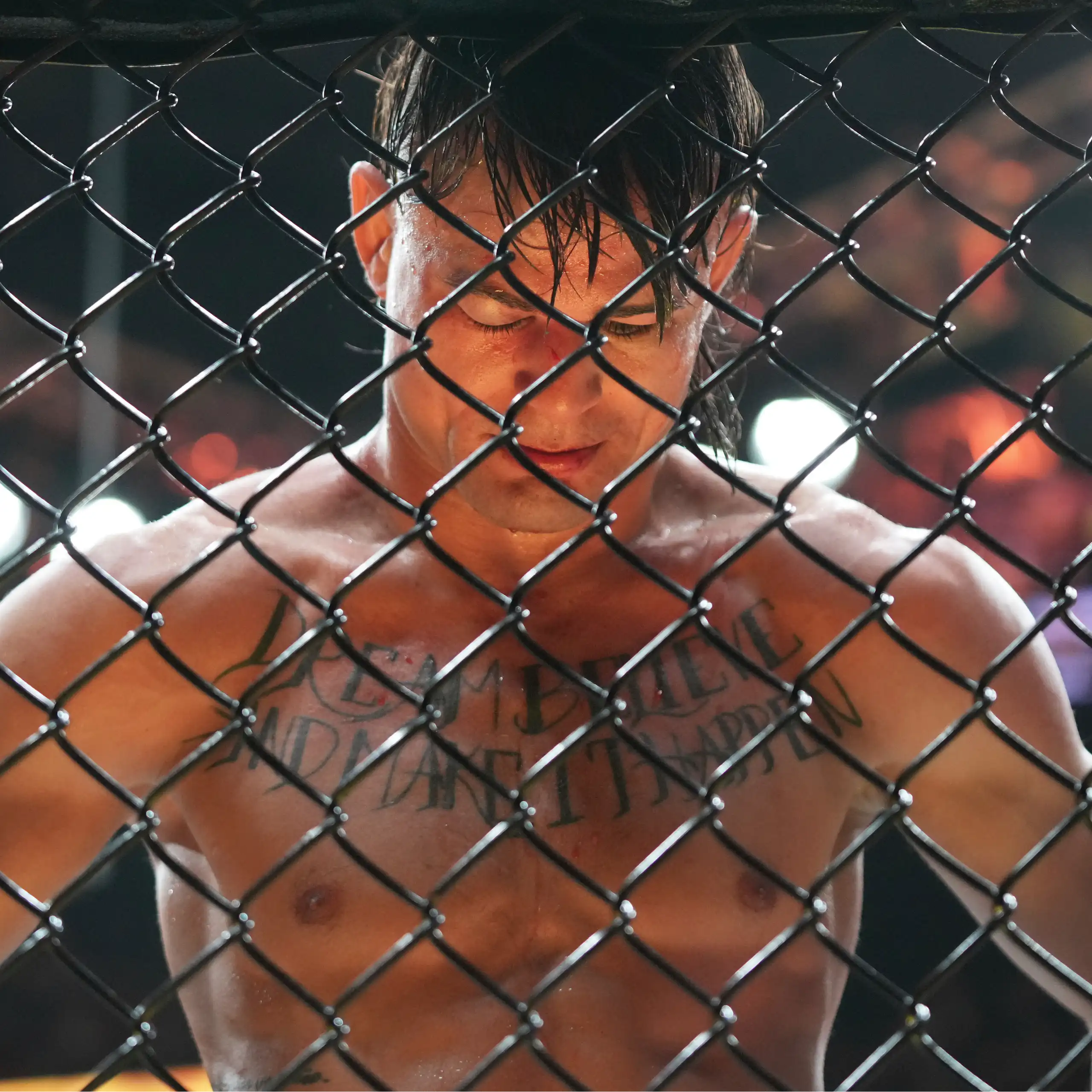 Un combattant UFC baisse la tête devant la grille de l'arène.