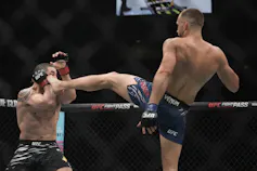 Un athlète de sport de combat assène un coup de talon à son adversaire
