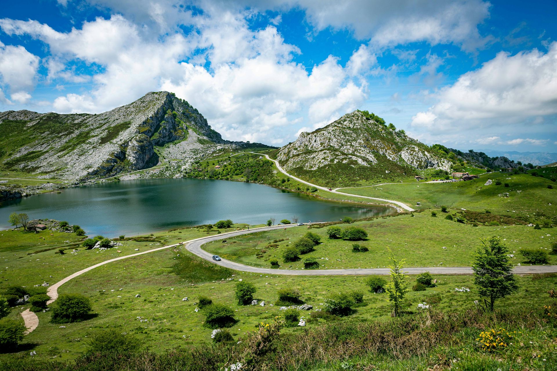 Vista de una pradera y un lago entre dos picos rocosos