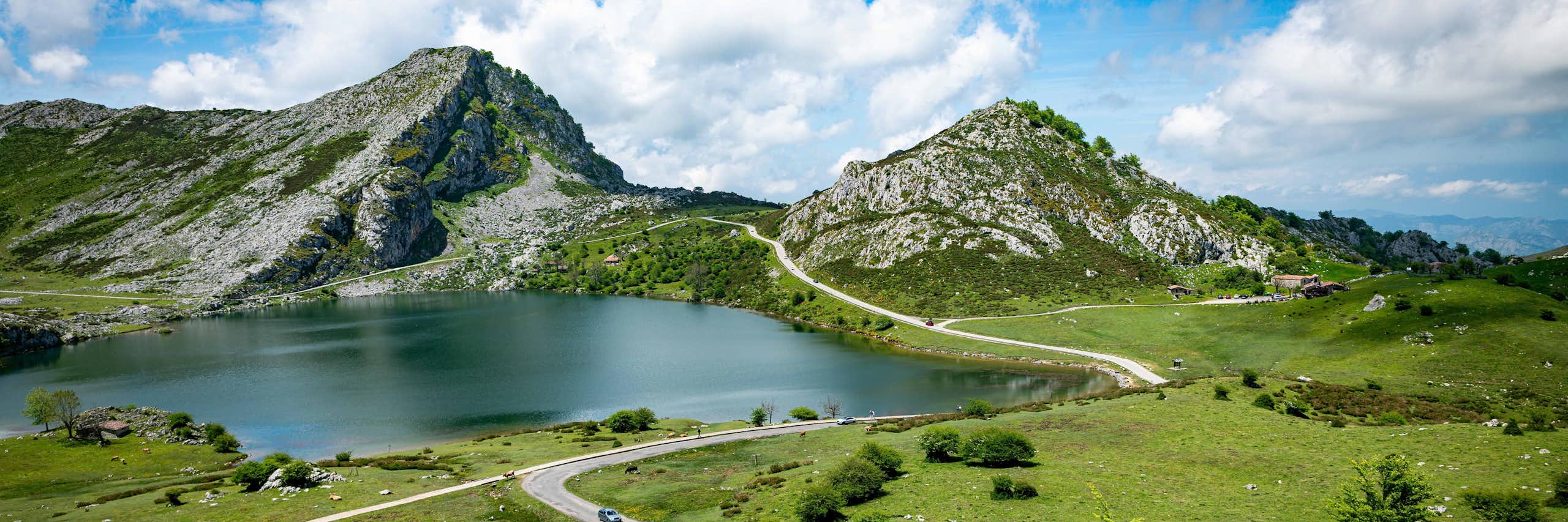 Vista de una pradera y un lago entre dos picos rocosos