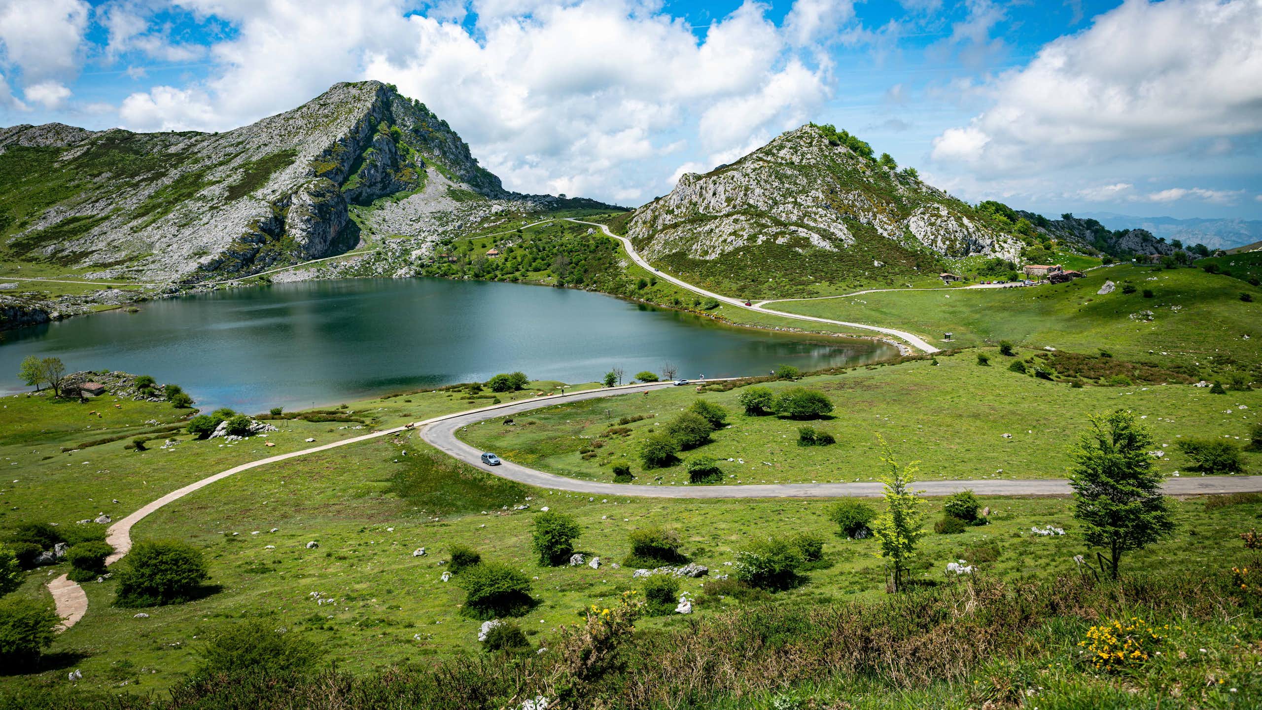 Vista de una pradera y un lago entre dos picos rocosos