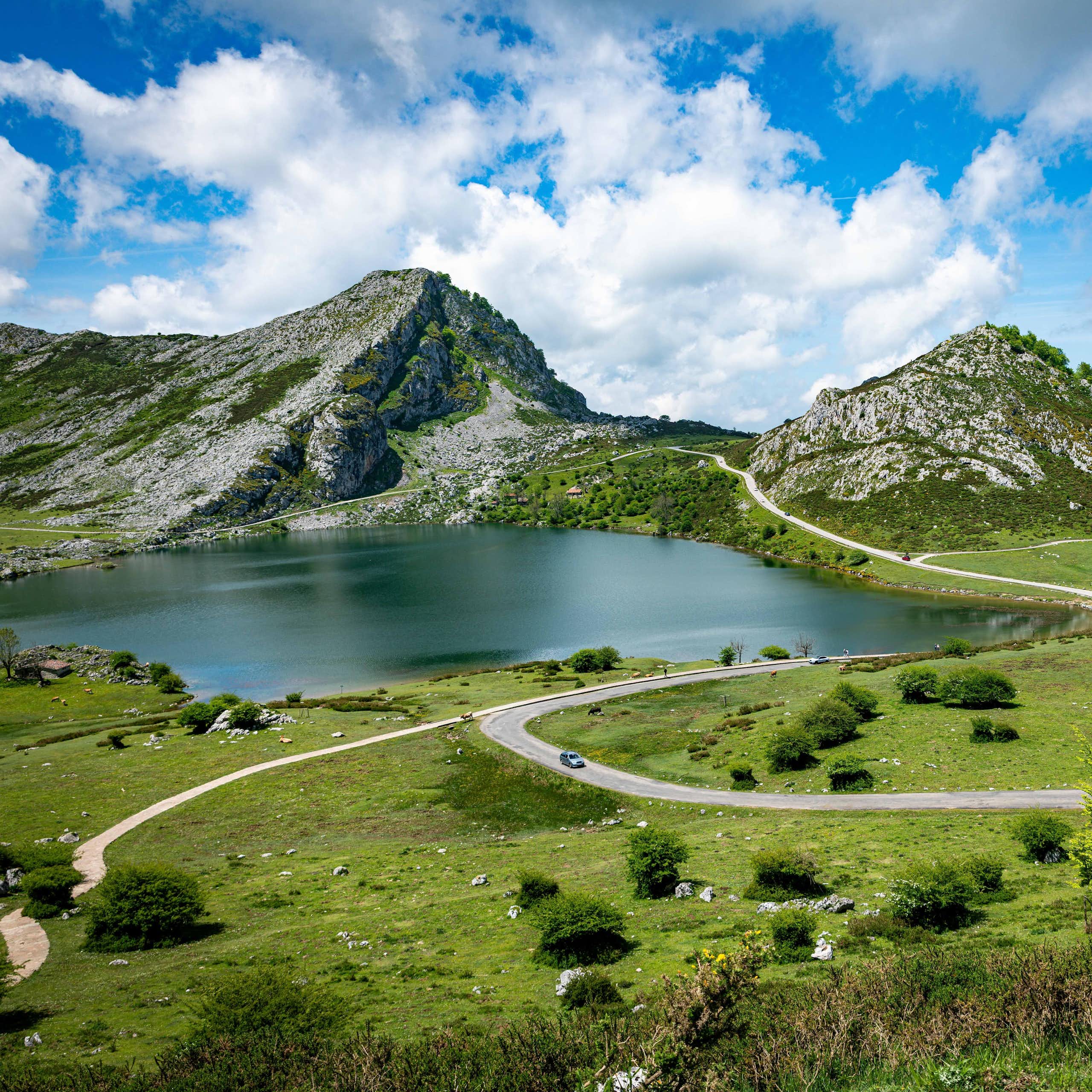 Vista de una pradera y un lago entre dos picos rocosos
