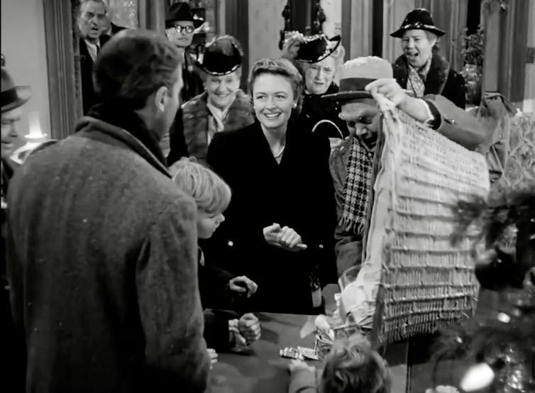 A group of smiling people dump a large basket of cash on a desk.