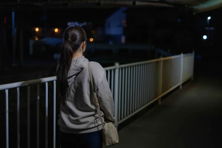 Woman walking along a street at night.