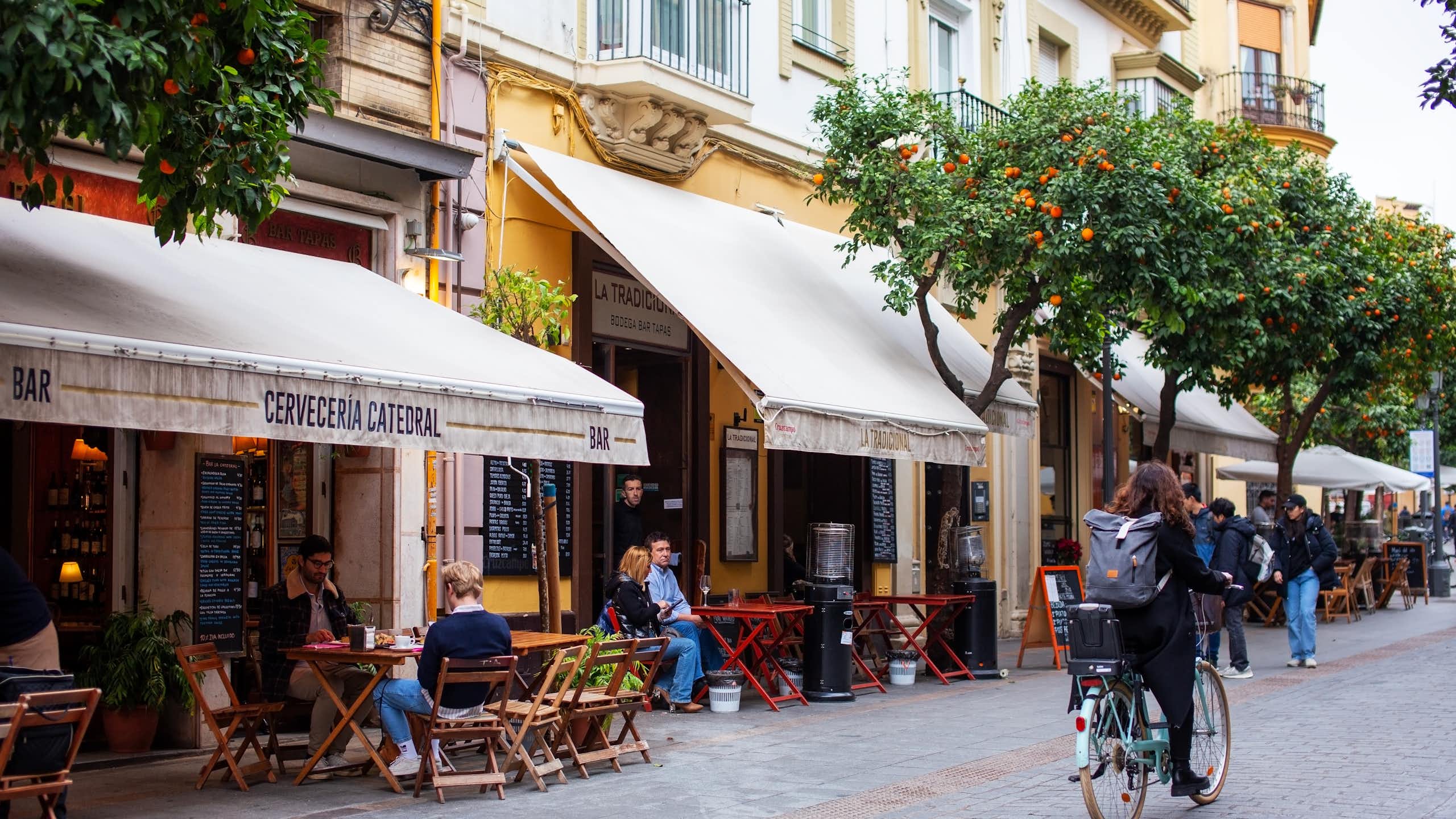 Una calle de Sevilla donde se pueden leer los nombres de varios establecimientos.
