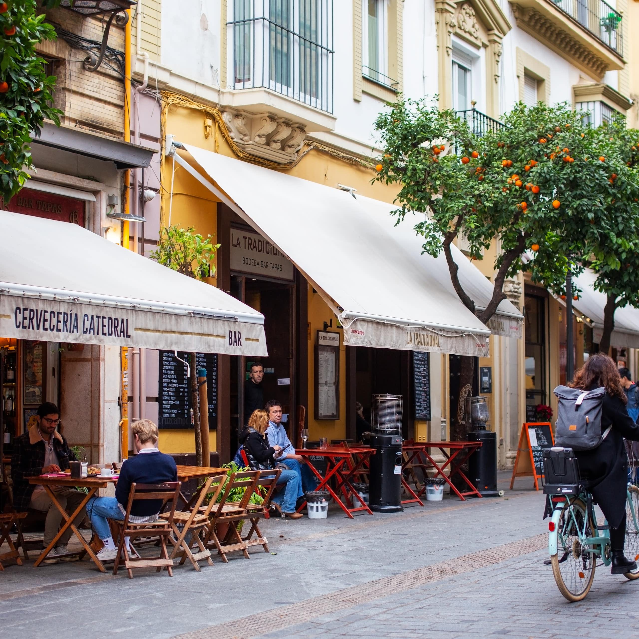 Una calle de Sevilla donde se pueden leer los nombres de varios establecimientos.