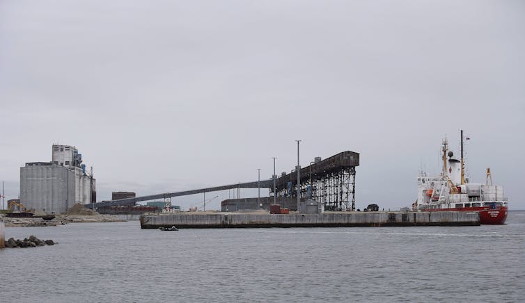 a large concrete structure near the water, a boat is docked nearby