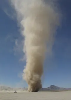 A large cone of dust rising out of a desert.