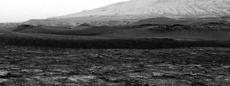 a gif of a tall, thin column of dust moving across a rocky landscape.