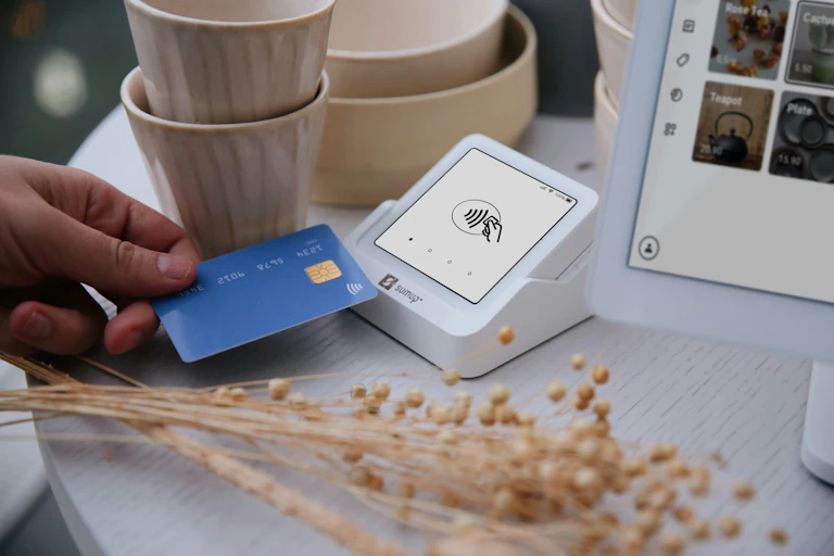 Customer tapping a blue credit card on the SumUp Solo card reader in a ceramics shop.