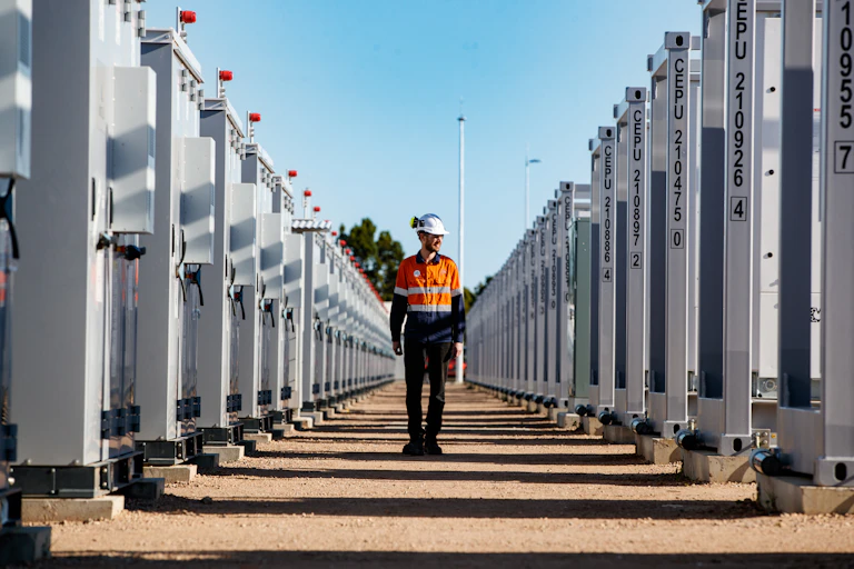 Worker walking through stacks of grid batteries
