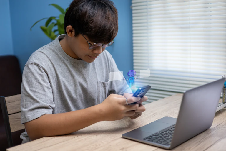 Adolescent assis à la maison utilisant son smartphone pour converser avec un chatbot.