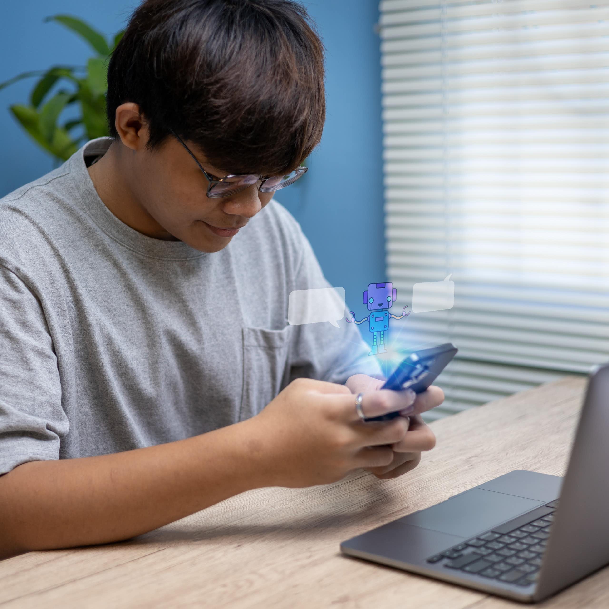 Adolescent assis à la maison utilisant son smartphone pour converser avec un chatbot.