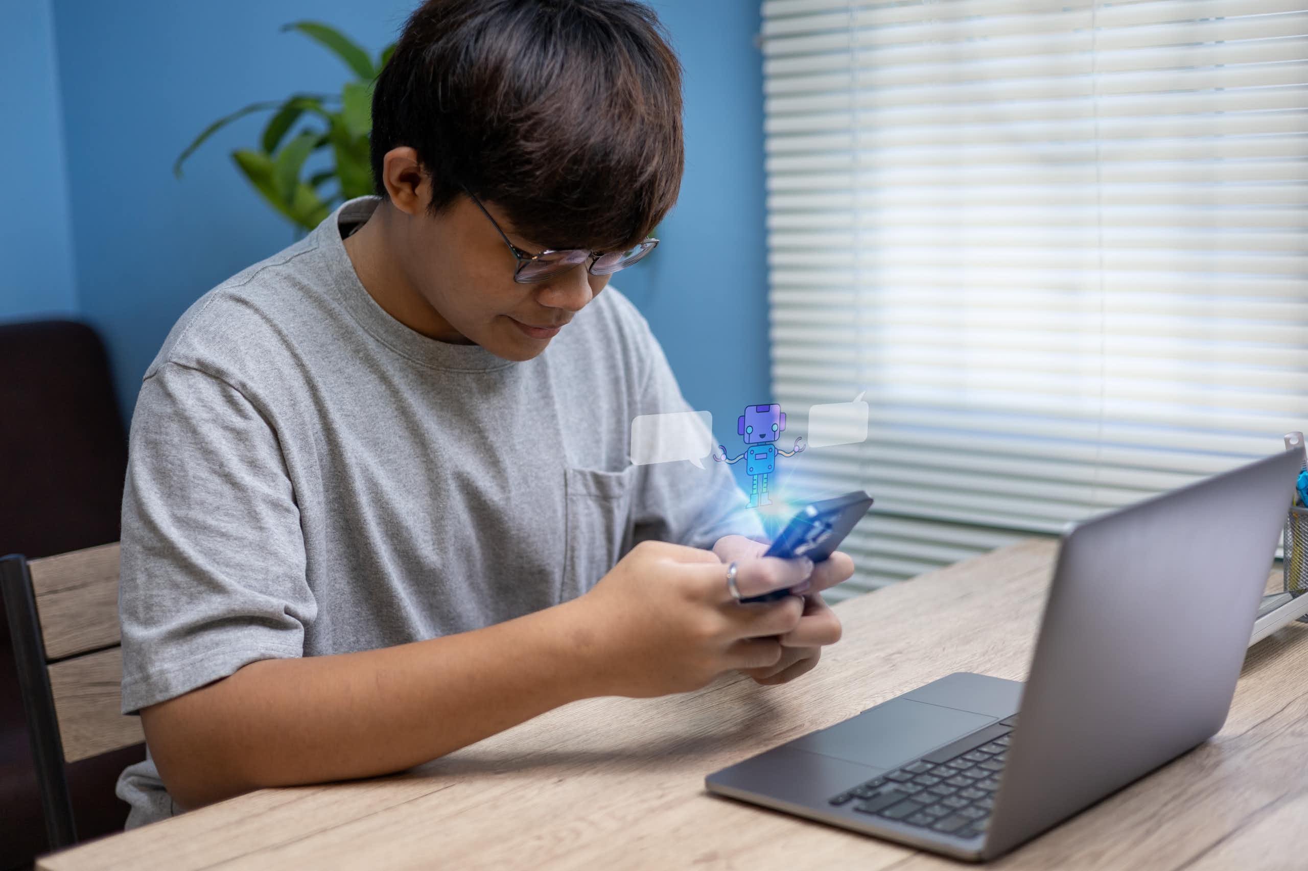 Adolescent assis à la maison utilisant son smartphone pour converser avec un chatbot.