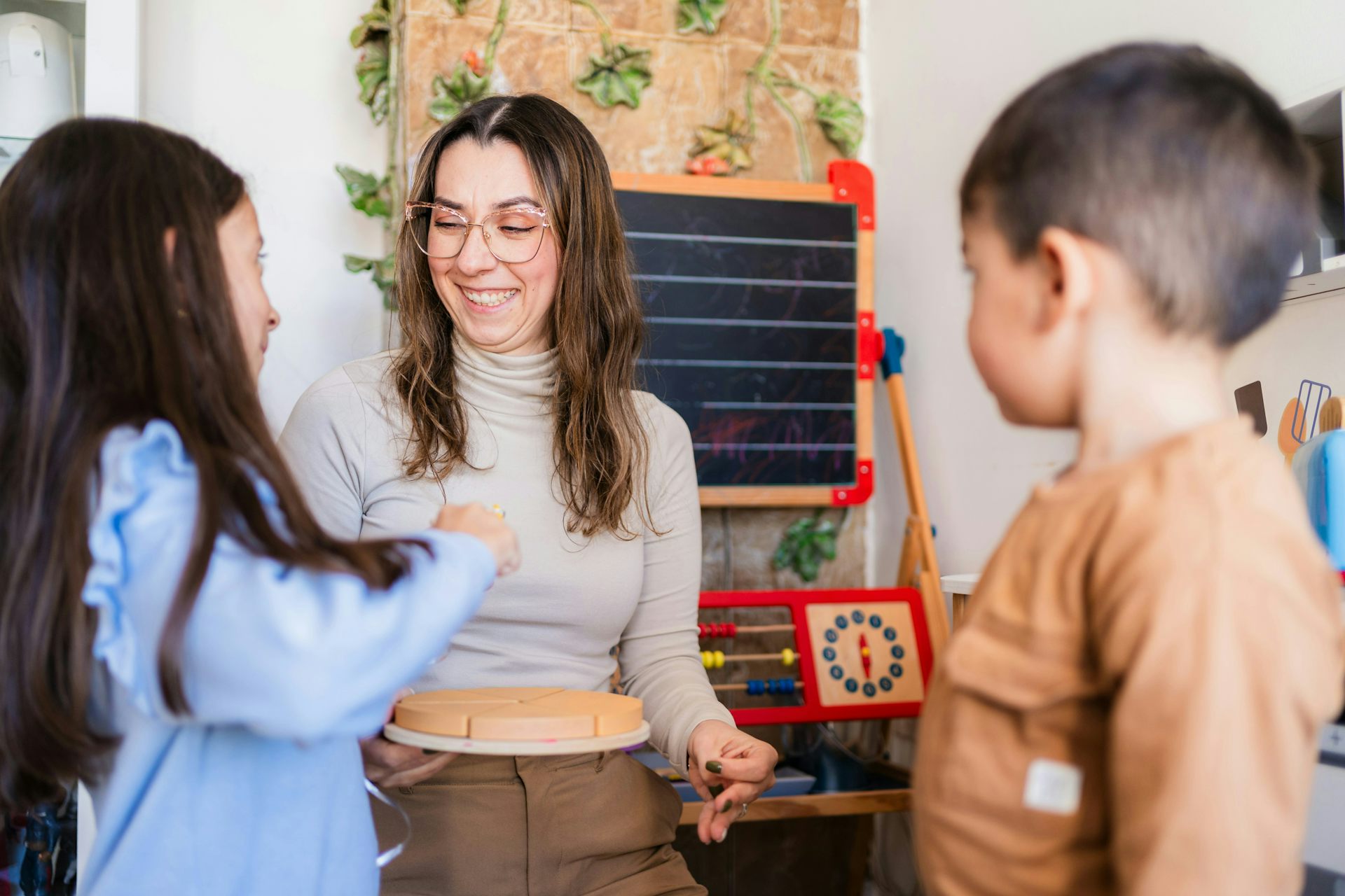 A teacher and two students, one of whom is touching a puzzle.