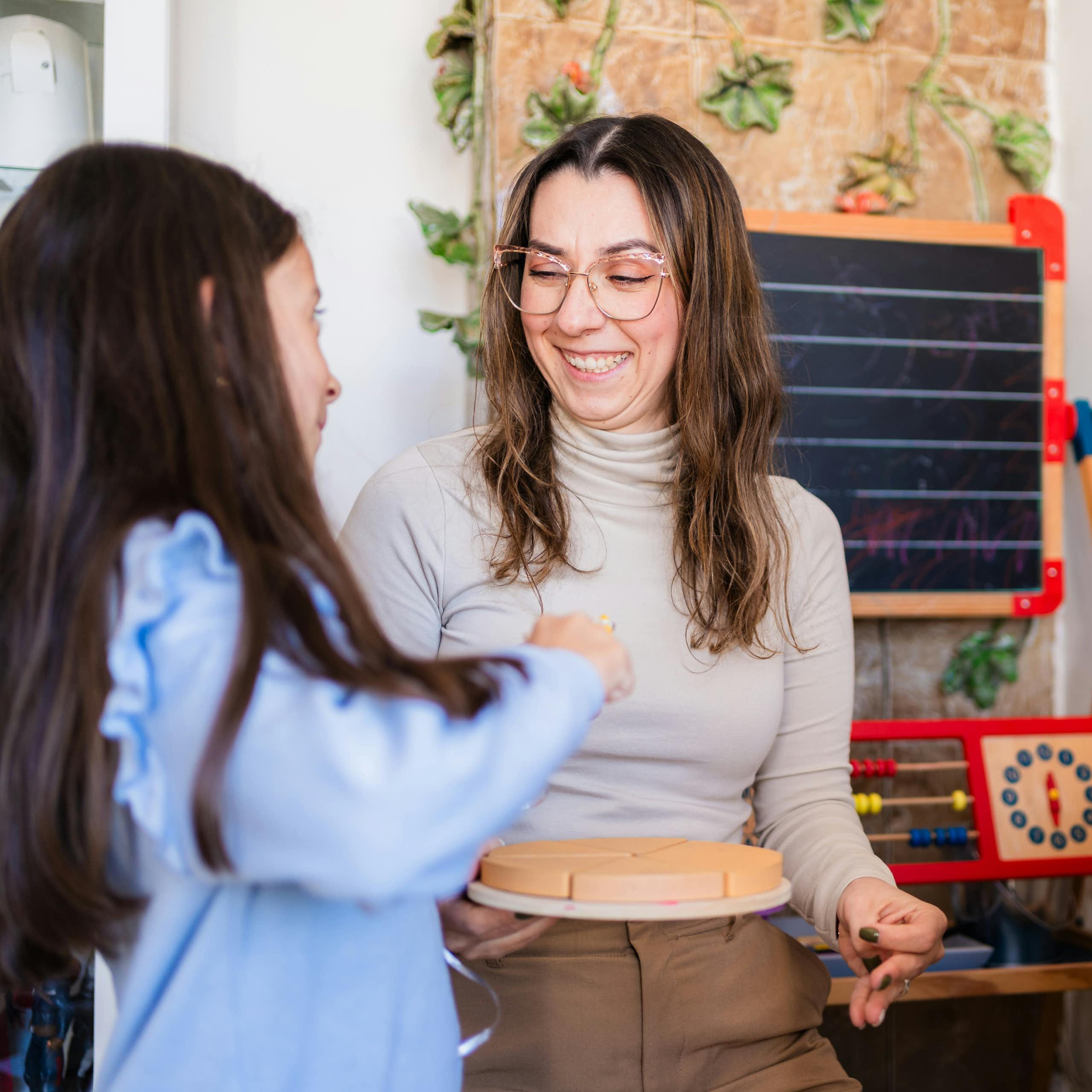 A teacher and two students, one of whom is touching a puzzle.