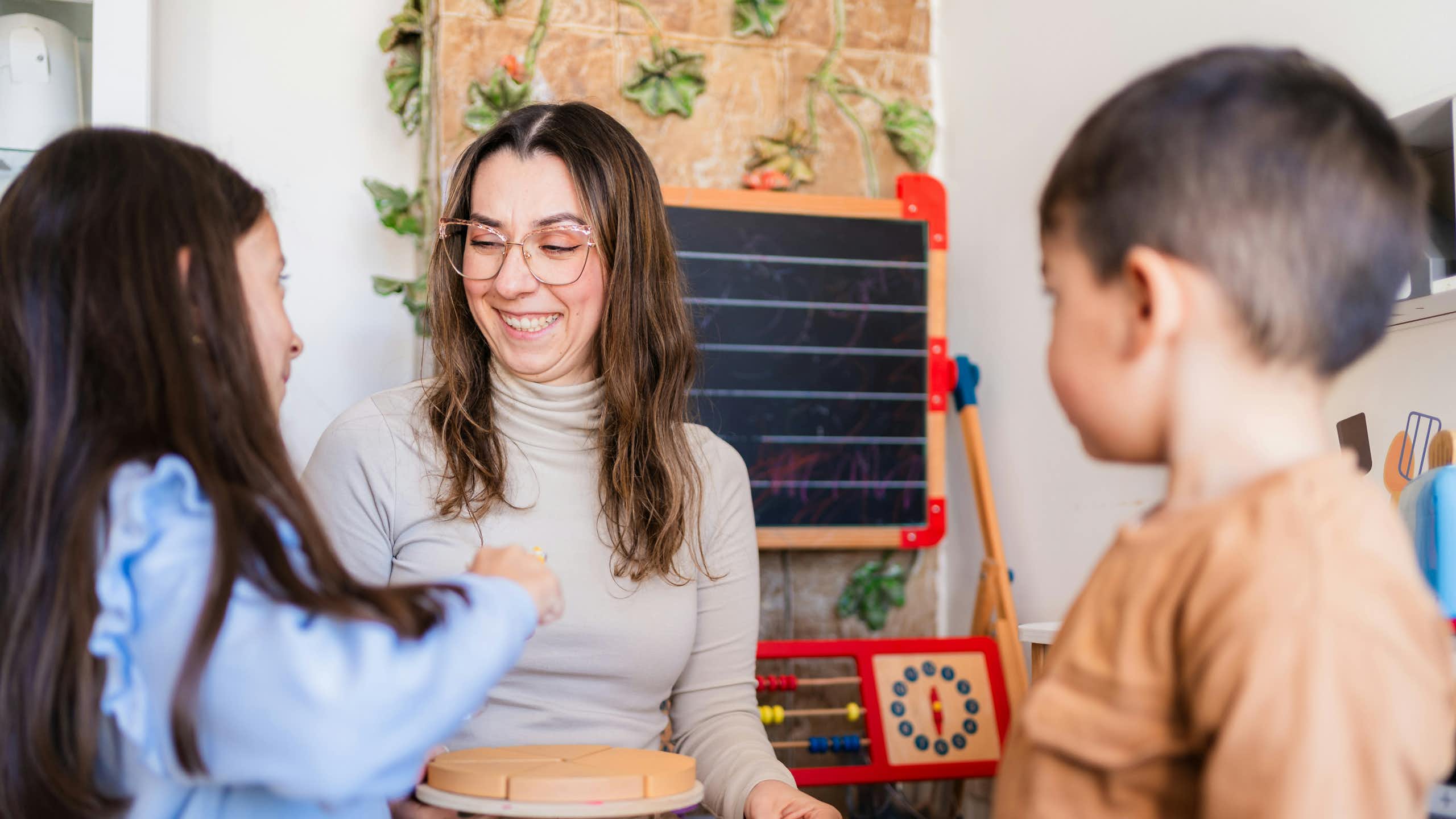 A teacher and two students, one of whom is touching a puzzle.