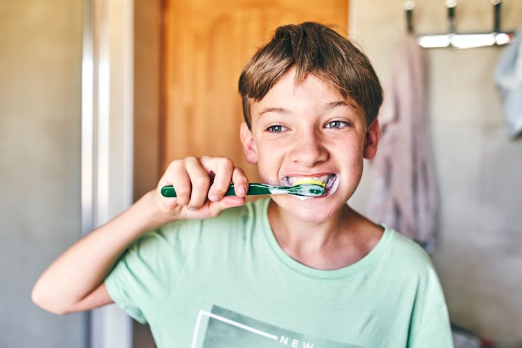 Boy brushes teeth with green toothbrush