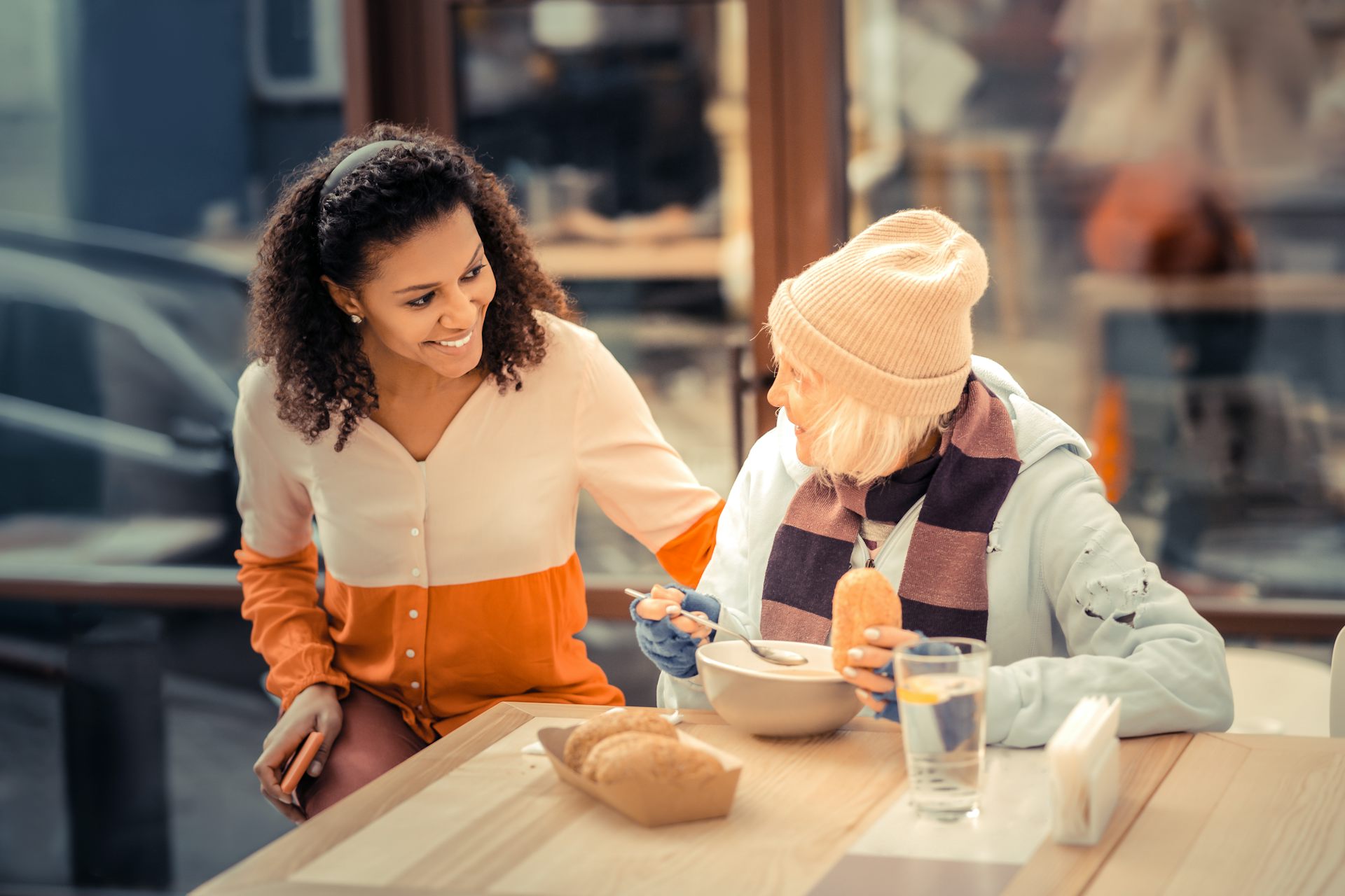 A young woman and older woman smiling at a table outdoors
