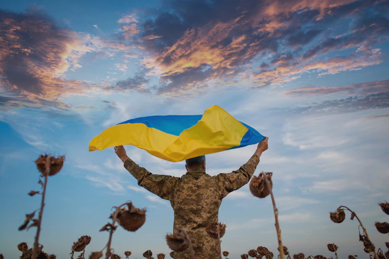 A Ukrainian soldier holds the national flag in a sunflower field.