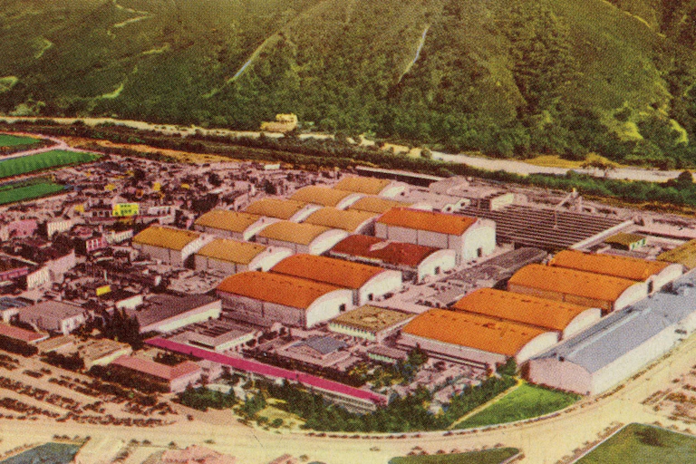 Colorful drawing of an aerial view of a sprawling movie studio, with lush hills in the background.