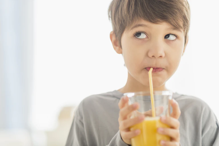 boys drinking orange juice from a straw