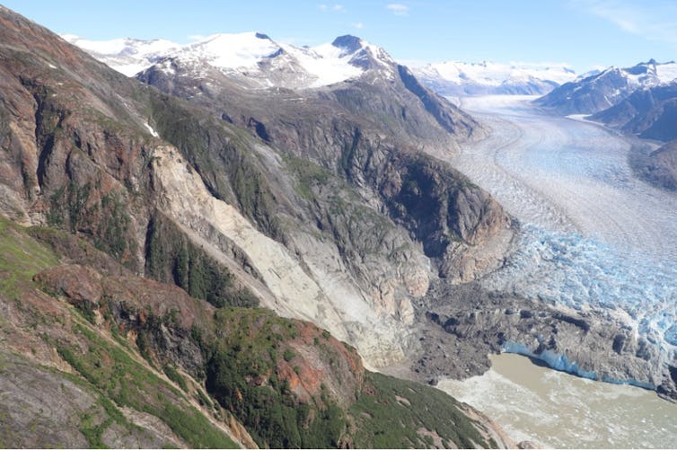 A mountain view shows where the retreating glacier and possible permafrost thaw influenced valley walls exposed above open water.