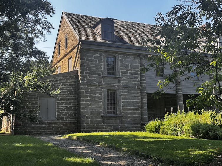 Exterior view of old stone building surrounded by grass and trees
