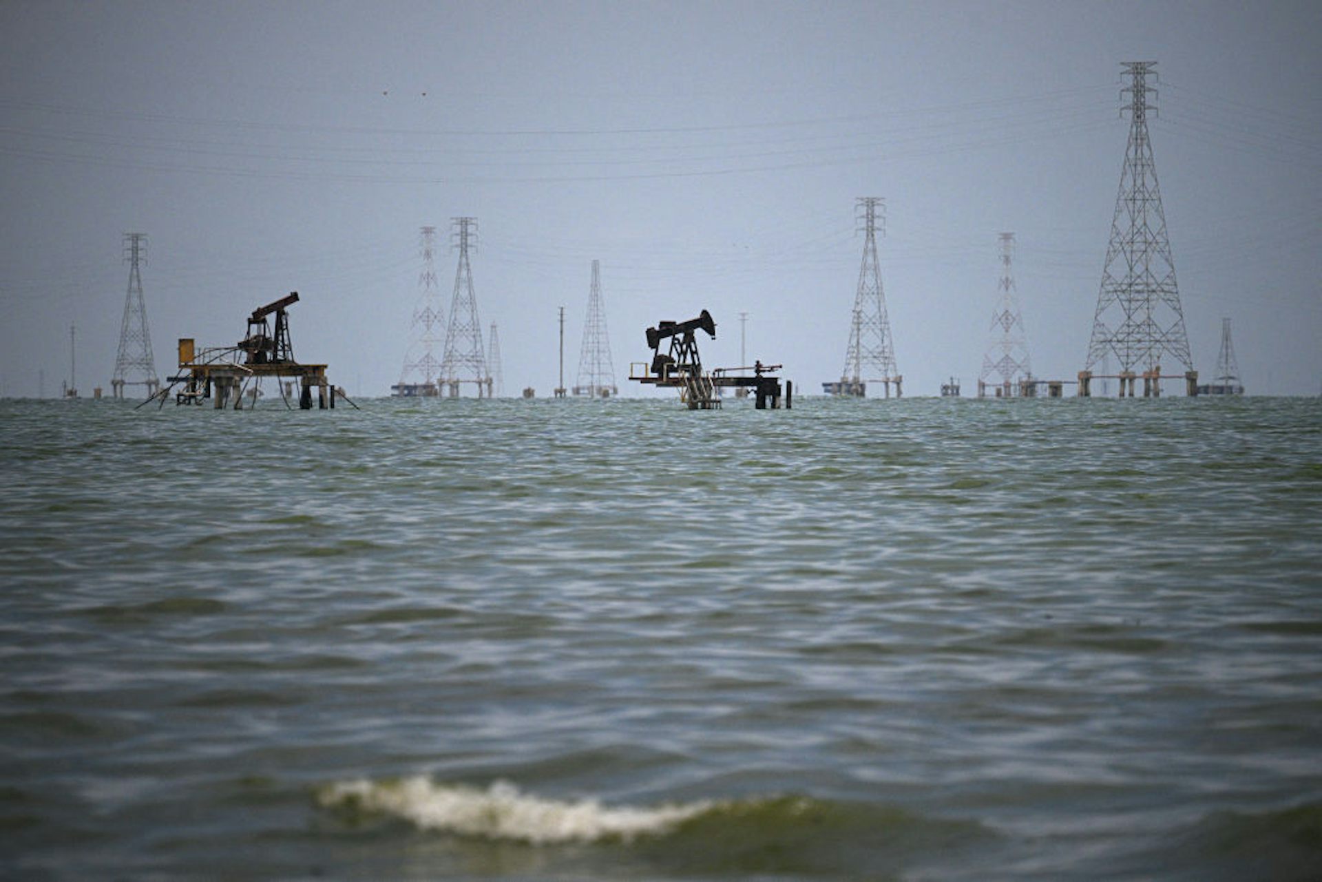 Oil rigs are seen on a large body of water.