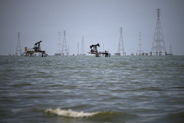 Oil rigs are seen on a large body of water.