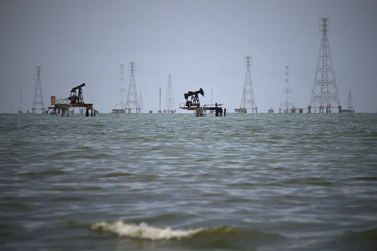 Oil rigs are seen on a large body of water.