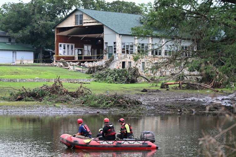 2025’s excessive climate had the jet move’s fingerprints everywhere it, from flash floods to hurricanes 2 Three people in a small boat on a river with a building behind them. The wall is torn off and debris is on the river banks.