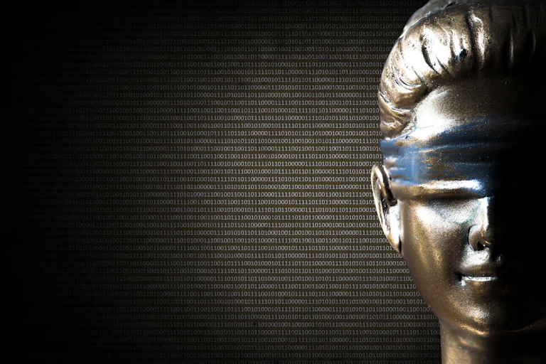 Una estatua con los ojos vendados y de la que emana una sucesión de ceros y unos.
