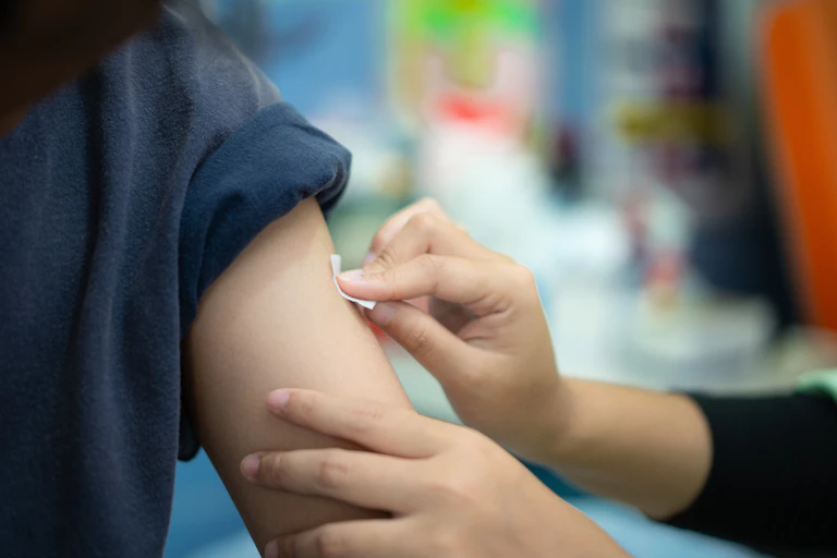 A medic swabbing a patient's arm prior to vaccinating them.