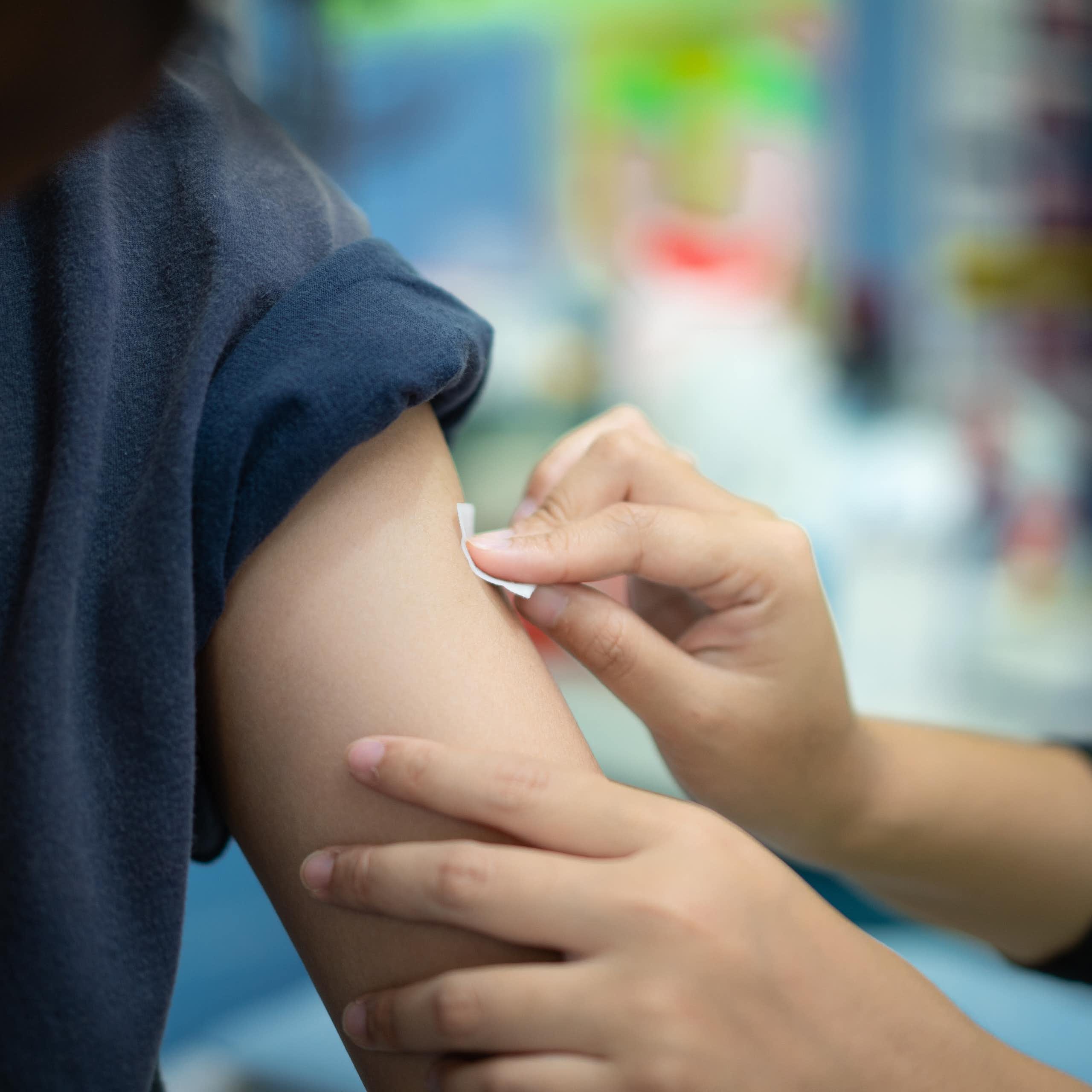 A medic swabbing a patient's arm prior to vaccinating them.