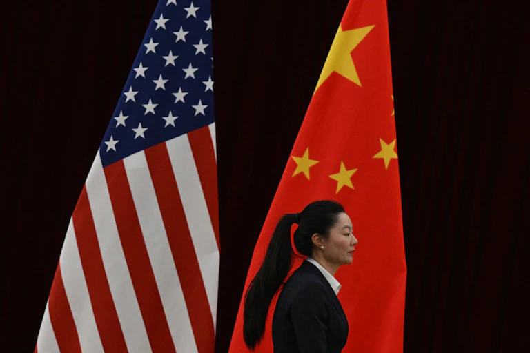 A woman walks past two flags.