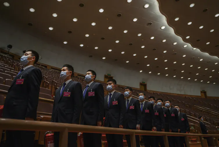 A line of men in suits with masks on.