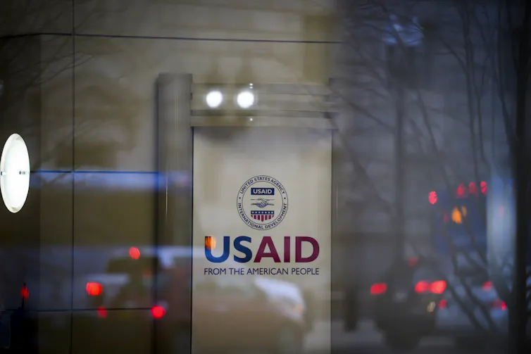 A sign saying USAID is seen behind glass.