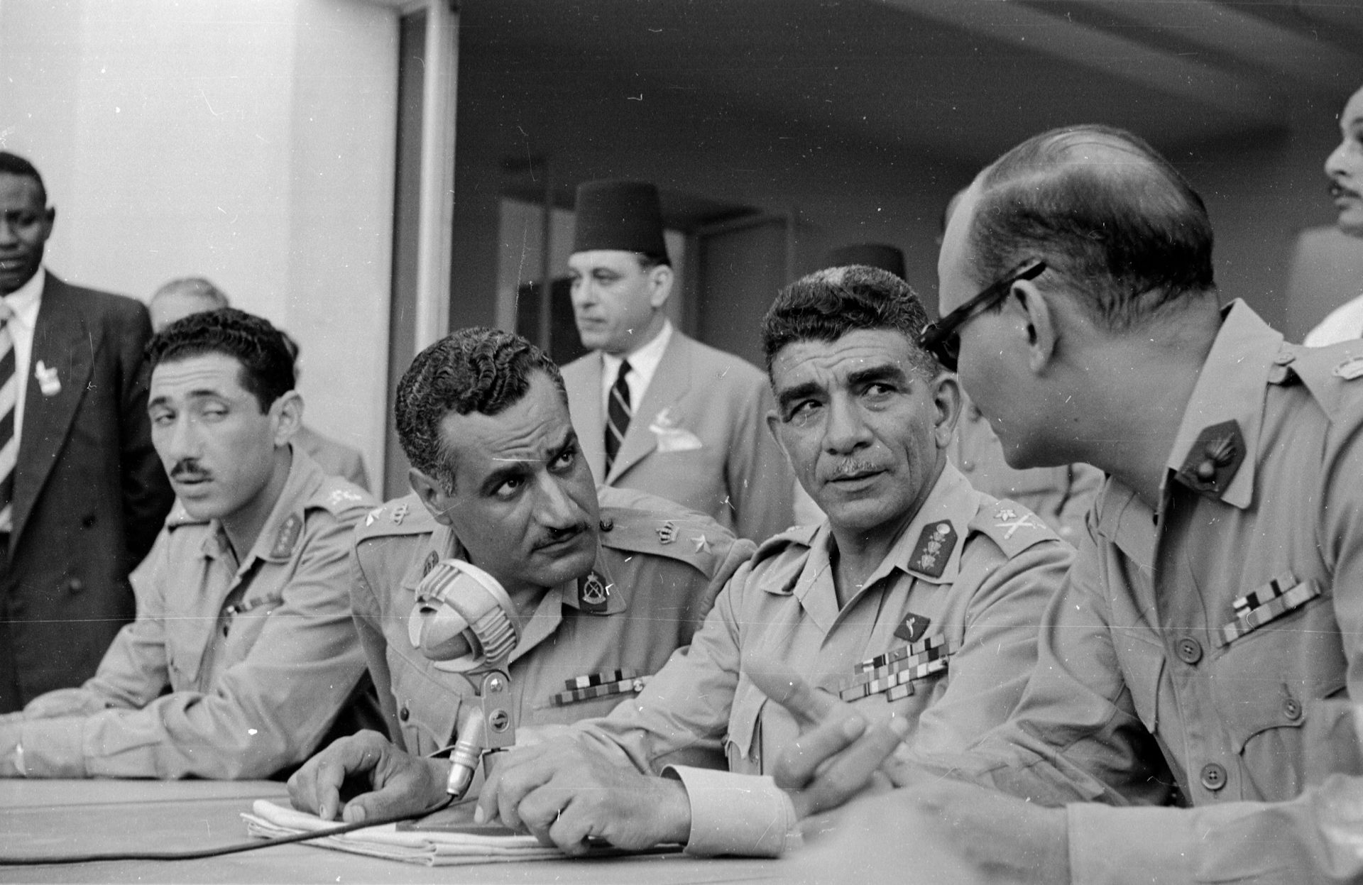 A group of men in army uniforms sit and chat.