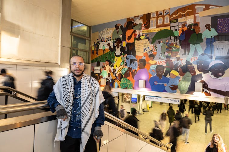 A young black person standing on the steps at Brixton underground station.
