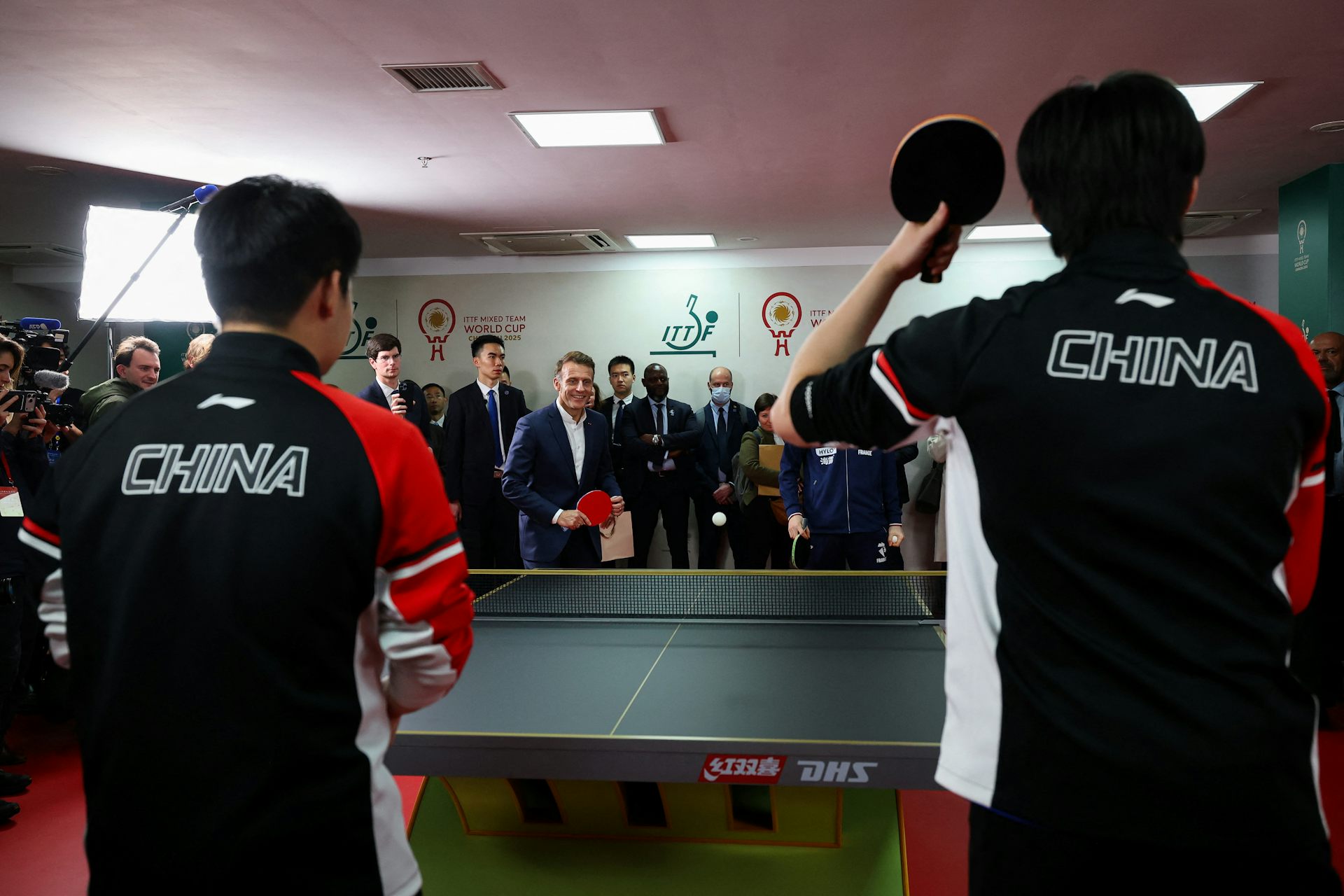 A man in a suit stands at a table tennis table.