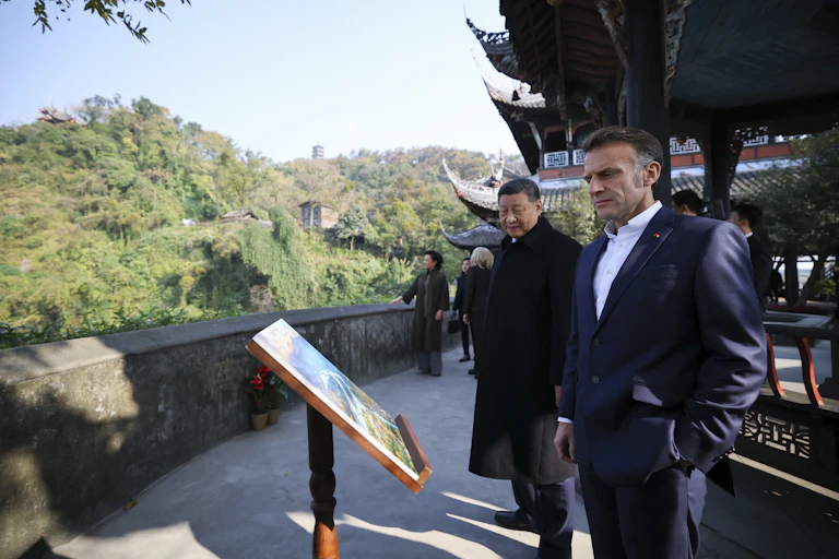 Two men look at an information board in front of a panoramic view.
