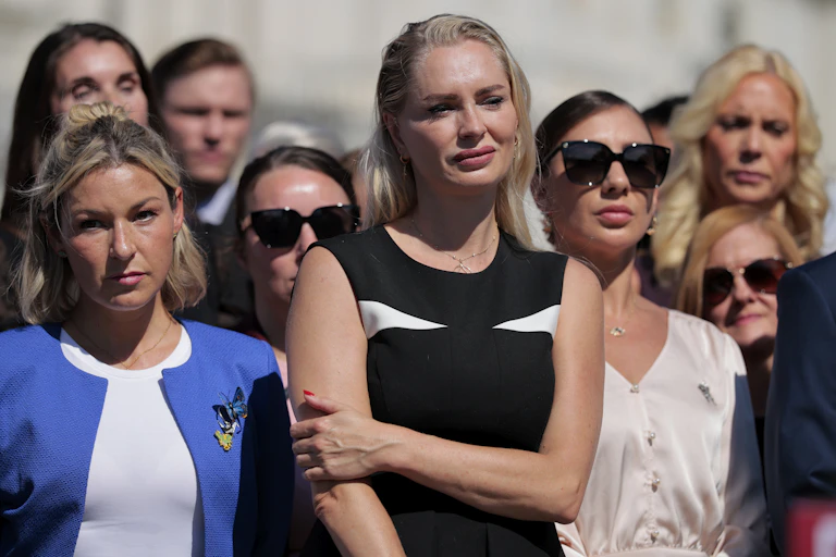 Women standing outside looking at someone not in the photo.